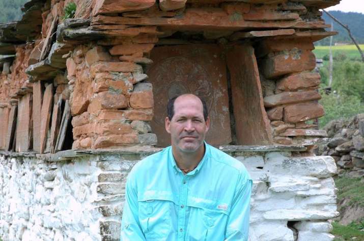 Mike Borre sits near a mani wall in Bumthang, Bhutan in 2006. Photo by Gerard Houghton. From Core of Culture