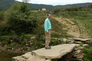 Mike Borre on a stone bridge leading to a chorten, Bhutan, 2006. Photo by Gerard Houghton. From Core of Culture