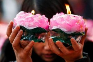 A woman holds candles as she prays at a Buddhist temple in Badachu Park, Beijing. From pinterest.com