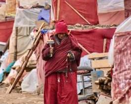 A Buddhist nun walks past a row of makeshift shelters at Yarchen Gar. From lesstraveledworld.com