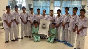 The Wild Boars football team with a portrait of Saman Kunan, upon which the boys have written messages of thanks. From cnn.com