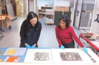 Research assistant Su Yen Chong with Haema Sivanesan examining woodcut prints by Shiko Munakata. From aggv.ca