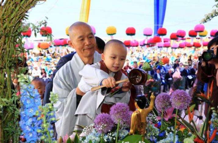 A monk and a novice bathe a Buddha statue together in commemoration of the Buddha’s birth. From asianews.it