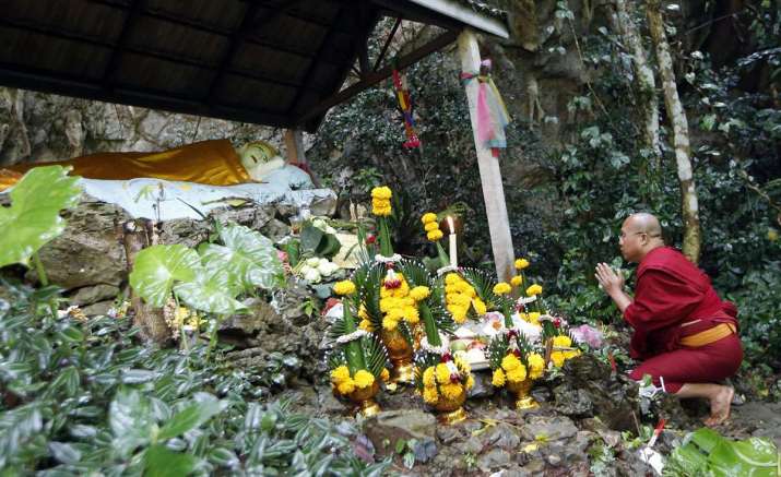 A Thai monk prays for the 12 boys and their coach at a shrine near the cave. From theatlantic.com