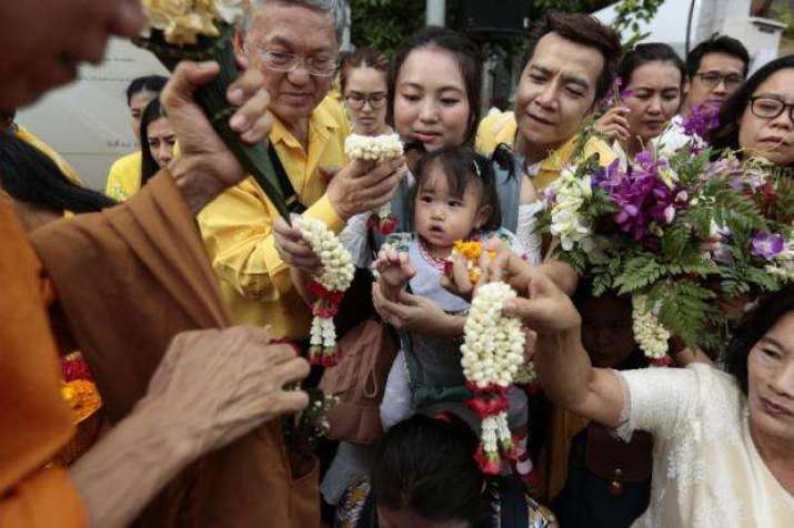 People offer flowers and other alms to Buddhist monastics to mark the beginning of the rains retreat. From bangkokpost.com