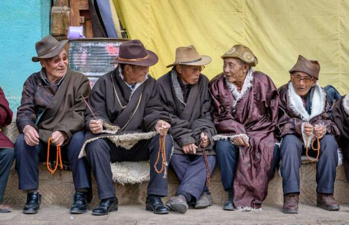 2018. Wu Village Lower Monastery outside Tong Ren. Older men watching the cham. The old men seem to sit in the same prime location every year. The Tibet Buddhist way seems to be: the old men sit with the old men, the old ladies sit with the old ladies, the single women sit with the single women, etc. I say “sit” but there are not enough seats so “stand” is often the way, especially for the younger people. This is not a hard and fast rule, sometimes the whole family or all the women and children in the family sit together.