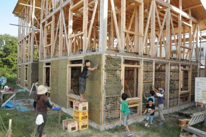 Local volunteers help build the earth-and-bamboo wall of the guesthouse at Tokurin-ji in 2013. From japantimes.co.jp