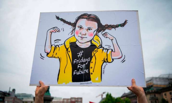 A protester holds a drawing of Greta Thunberg. From theguardian.com