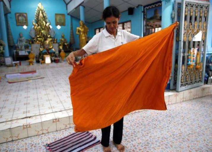 A volunteer folds a monastic robe made from recycled plastic bottles at Wat Chak Daeng. From news4europe.eu