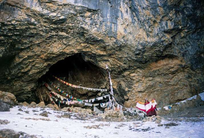 Lama Lhundrup Dorje holds out the ends of his red and white tantric shawl in a simulation of yogic flight, while standing in front of the cave where eighth-century princess-yogini Yeshe Tsogyal attained enlightenment by practicing tummo, the yoga of fierce heat. Khandro Sangpuk, Terdrom,Tibet. Photo by Ian Baker