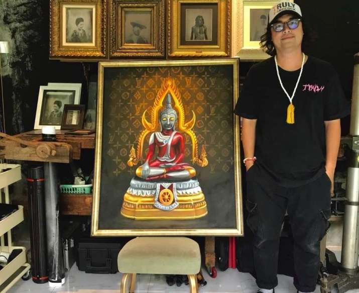 An auction organizer poses next to an “Ultraman Buddha” painting. From khaosodenglish.com