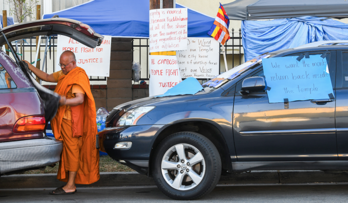 Ven. Granderson Path unloads a van at a protest outside of Khemara Buddhikaram earlier this month. From lbpost.com