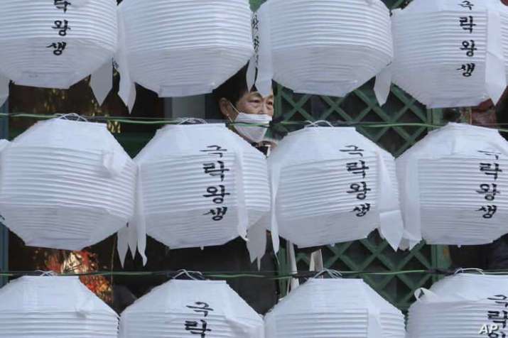 A woman in a mask visits the Jogye temple in Seoul. From voanews.com