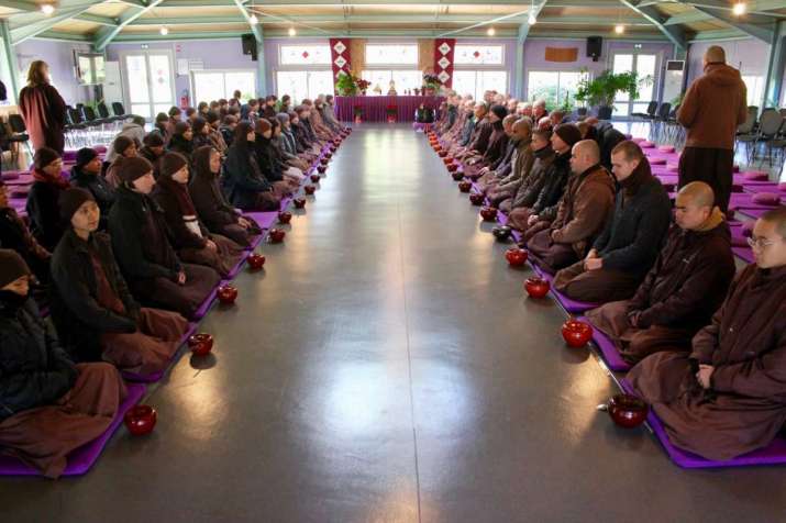 Monastics of Thich Nhat Hanh’s Plum Village community sit for a formal lunch in a meditation hall. From crcc.usc.edu