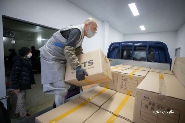 Ven. Pomnyun Sunim joins Jungto Society volunteers in loading the boxes for delivery. Image courtesy of Jungto Society